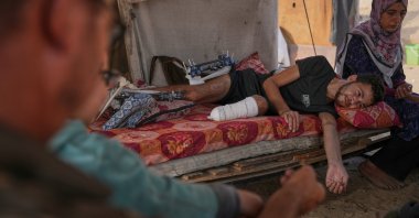 Yassin Marouf, 23, who lost his left foot and suffered a severe injury to his right leg after being hit by Israeli shelling in May, lies in a tent surrounded by his family in Zawaida, central Gaza, Palestine, Nov. 6, 2025. (AP Photo)