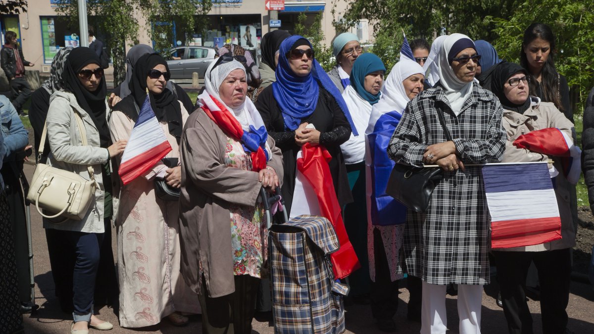 Women wearing Muslim headscarves and holding French flags gather outside the town hall of Mantes-la-Ville, Paris, France, May 16, 2014. (AP Photo)