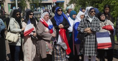 Women wearing Muslim headscarves and holding French flags gather outside the town hall of Mantes-la-Ville, Paris, France, May 16, 2014. (AP Photo)