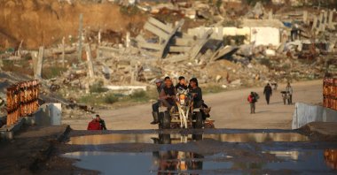 Palestinians ride a donkey cart past buildings and homes destroyed by the Israeli military, central Gaza Strip, Palestine, Dec. 13, 2025. (AFP Photo)