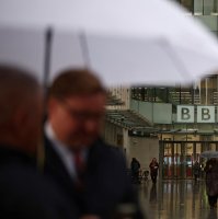 People shelter from the rain outside the entrance to the BBC in London. U.K. Nov. 10, 2025. (AFP Photo)