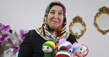 Zehra Bağcı poses with the handmade dolls she knits for children living without family support, Yozgat, Türkiye, Dec. 5, 2025. (AA Photo)