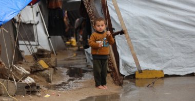 A Palestinian child stands among flooded tents at a camp for war-displaced, in al-Mawasi neighborhood, Gaza Strip, Palestine, Dec. 16, 2025. 
