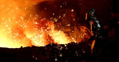 A steelworker stands amid sparks of raw iron coming from a blast furnace at a ThyssenKrupp steel factory in Duisburg, Germany, Nov. 5, 2025. (Reuters Photo)
