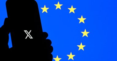 This illustration photograph shows the logo of X (formerly Twitter) social network displayed on a smartphone in front a European Union flag in Brussels, Belgium, Sept. 29, 2025. (AFP Photo)