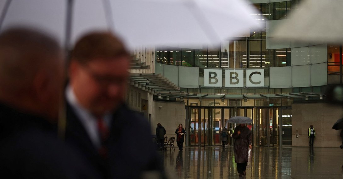 People shelter from the rain outside the entrance to the BBC in London. U.K. Nov. 10, 2025. (AFP Photo)