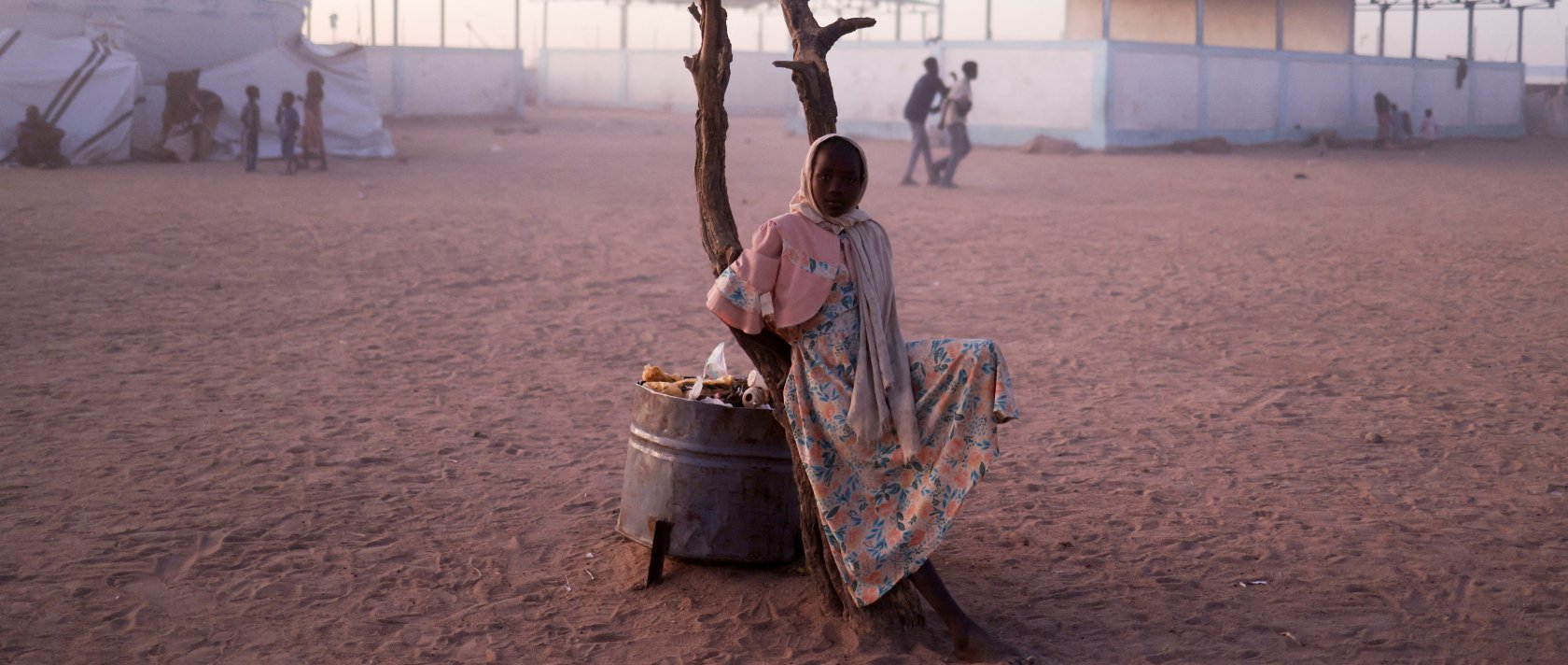 A Sudanese refugee girl from el-Fasher rests next to a burnt tree in the middle of the Tine transit camp, eastern Chad, Nov. 23, 2025. (Reuters Photo)