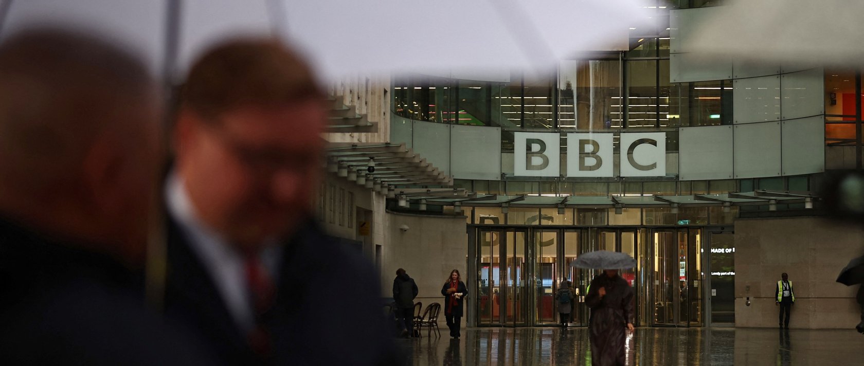 People shelter from the rain outside the entrance to the BBC in London. U.K. Nov. 10, 2025. (AFP Photo)