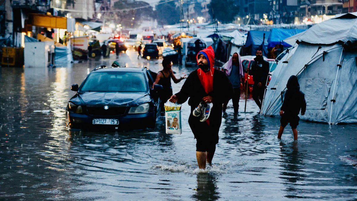 Displaced Palestinians wade through floodwaters following heavy rains in Gaza City, central Gaza Strip, Palestine, Dec. 15, 2025. (AFP Photo)