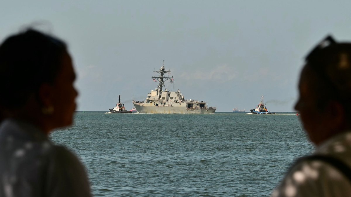 People watch the USS Gravely, a U.S. Navy warship, departing the Port of Port of Spain, Oct. 30, 2025. (AFP Photo)