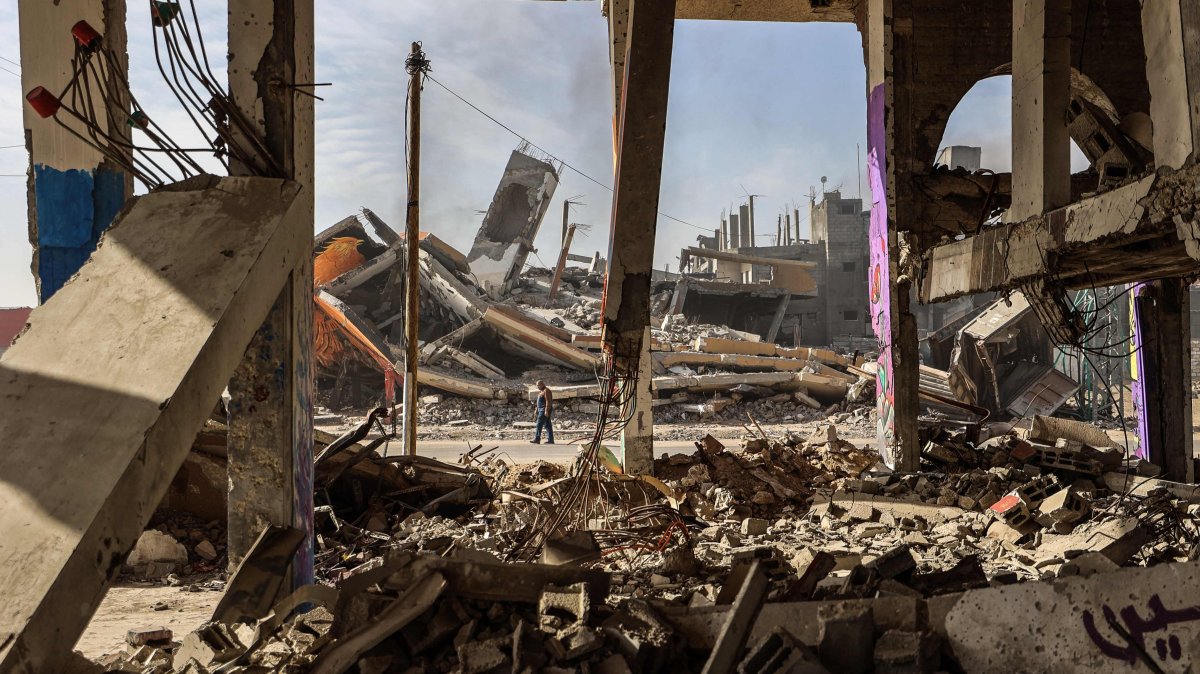 A man carrying walks past destroyed buildings partially covered in murals in the Maghazi refugee camp outside Deir al-Balah, Dec. 8, 2025. (AFP Photo)