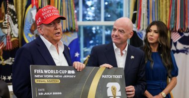 U.S. President Donald Trump (L) and FIFA president Gianni Infantino (C) hold a 2026 FIFA World Cup final match ticket in the Oval Office at the White House, Washington, U.S., Aug. 22, 2025. (Reuters Photo)