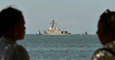 People watch the USS Gravely, a U.S. Navy warship, departing the Port of Port of Spain, Oct. 30, 2025. (AFP Photo)
