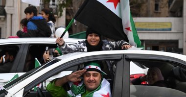 A boy waves a Syrian flag as they celebrate a year since the ousting of longtime ruler Bashar Assad in the capital Damascus, Syria, Dec. 8, 2025. (AFP Photo)