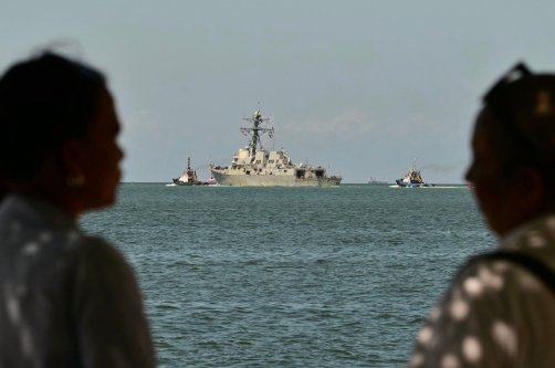 People watch the USS Gravely, a U.S. Navy warship, departing the Port of Port of Spain, Oct. 30, 2025. (AFP Photo)