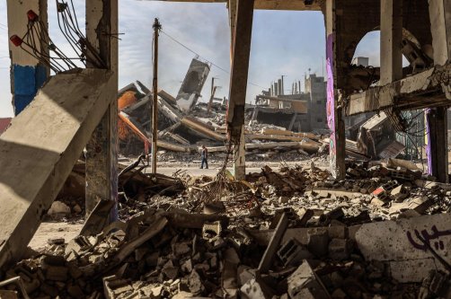 A man carrying walks past destroyed buildings partially covered in murals in the Maghazi refugee camp outside Deir al-Balah, Dec. 8, 2025. (AFP Photo)