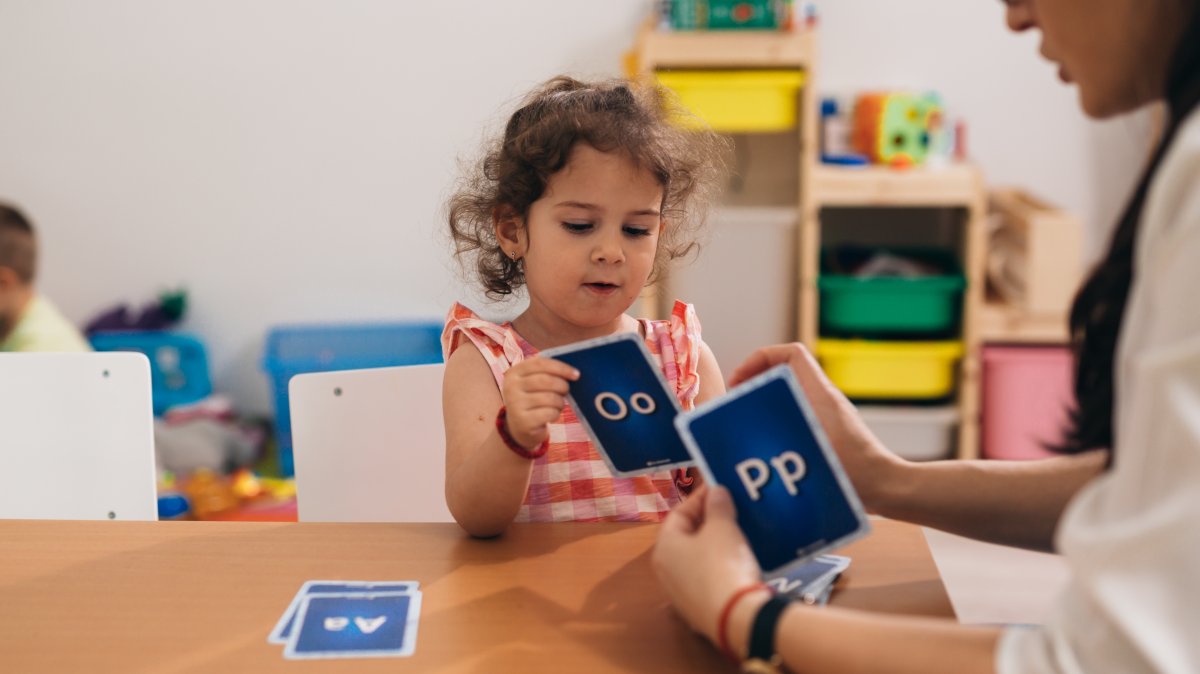 A teacher helps a child practice correct word pronunciation during a learning session. (Shutterstock Photo)