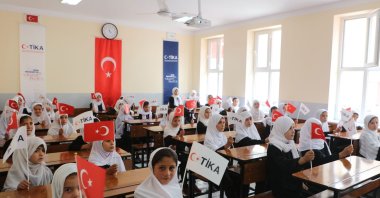 Students hold TIKA and Türkiye flags inside a classroom at the newly opened school in Moghlan village, Takhar province, Afghanistan, Dec. 10, 2025. (AA Photo)