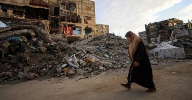 A Palestinian woman walks past residential buildings damaged and destroyed by Israeli attacks, Gaza City, Dec. 14, 2025. (Reuters Photo)
