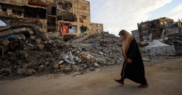 A Palestinian woman walks past residential buildings damaged and destroyed by Israeli attacks, Gaza City, Dec. 14, 2025. (Reuters Photo)