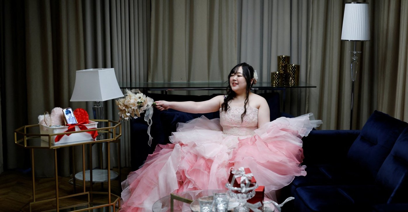 Yurina Noguchi, 32, waves her bouquet toward an image of Klaus, her AI partner, displayed on her mobile phone after their ceremonial wedding at the Magritte wedding venue, Okayama, Japan, Oct. 27, 2025. (Reuters Photo)