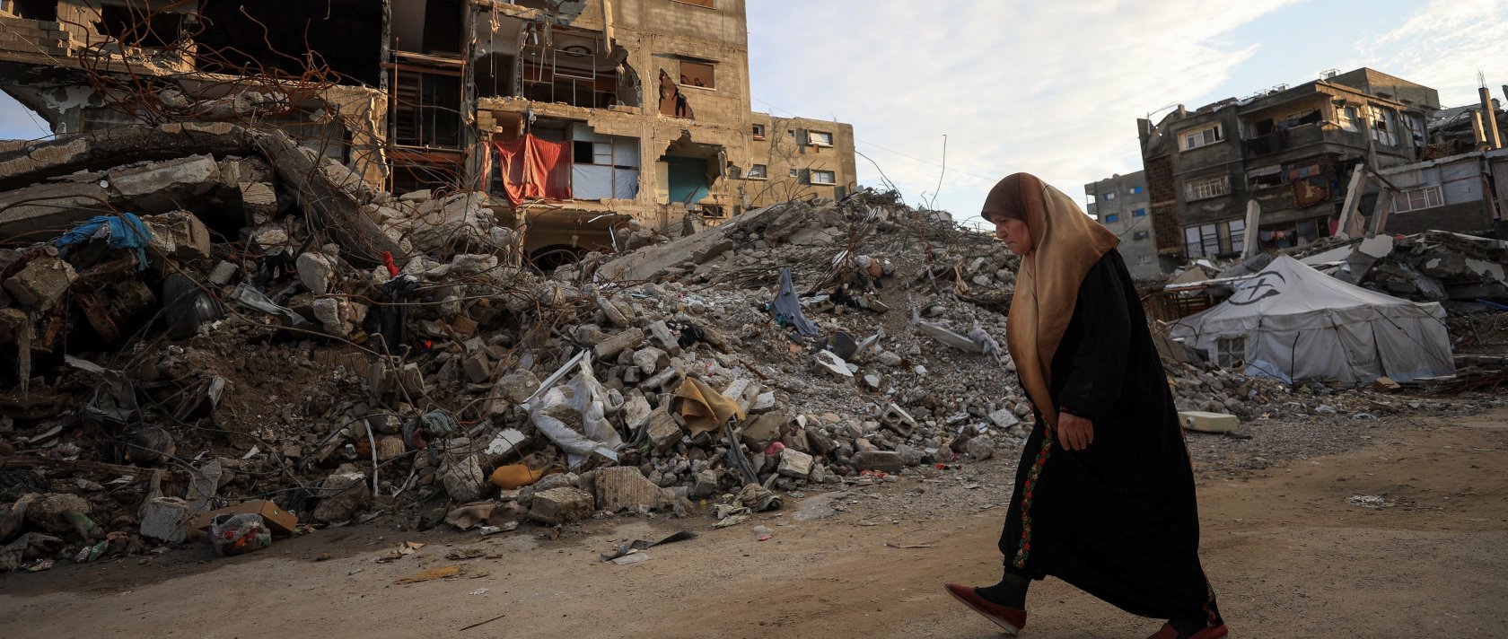 A Palestinian woman walks past residential buildings damaged and destroyed by Israeli attacks, Gaza City, Dec. 14, 2025. (Reuters Photo)