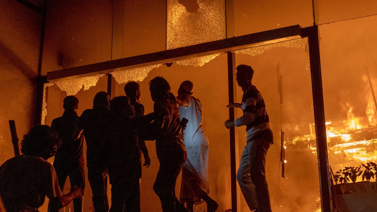 People are seen at the entrance to the Daily Star building as it burns amid protests following the news of the death of youth leader Sharif Osman Hadi, Dhaka, Bangladesh, Dec. 19, 2025. (AFP Photo)