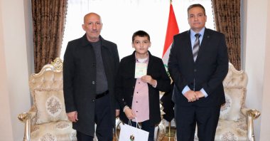 Ali Gazi Mohammed Jameel (C), with his uncle (L), holds his Iraqi identity card at the Iraqi Embassy, Ankara, Türkiye, Dec. 18, 2025. (DHA Photo)