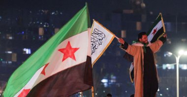 A person holds flags as people celebrate after the U.S.-backed YPG terrorist group signed a deal agreeing to integrate into Syria's new state institutions, Damascus, Syria, March 11, 2025. (Reuters Photo)