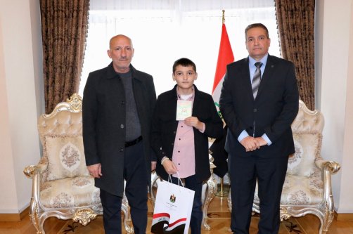 Ali Gazi Mohammed Jameel (C), with his uncle (L), holds his Iraqi identity card at the Iraqi Embassy, Ankara, Türkiye, Dec. 18, 2025. (DHA Photo)