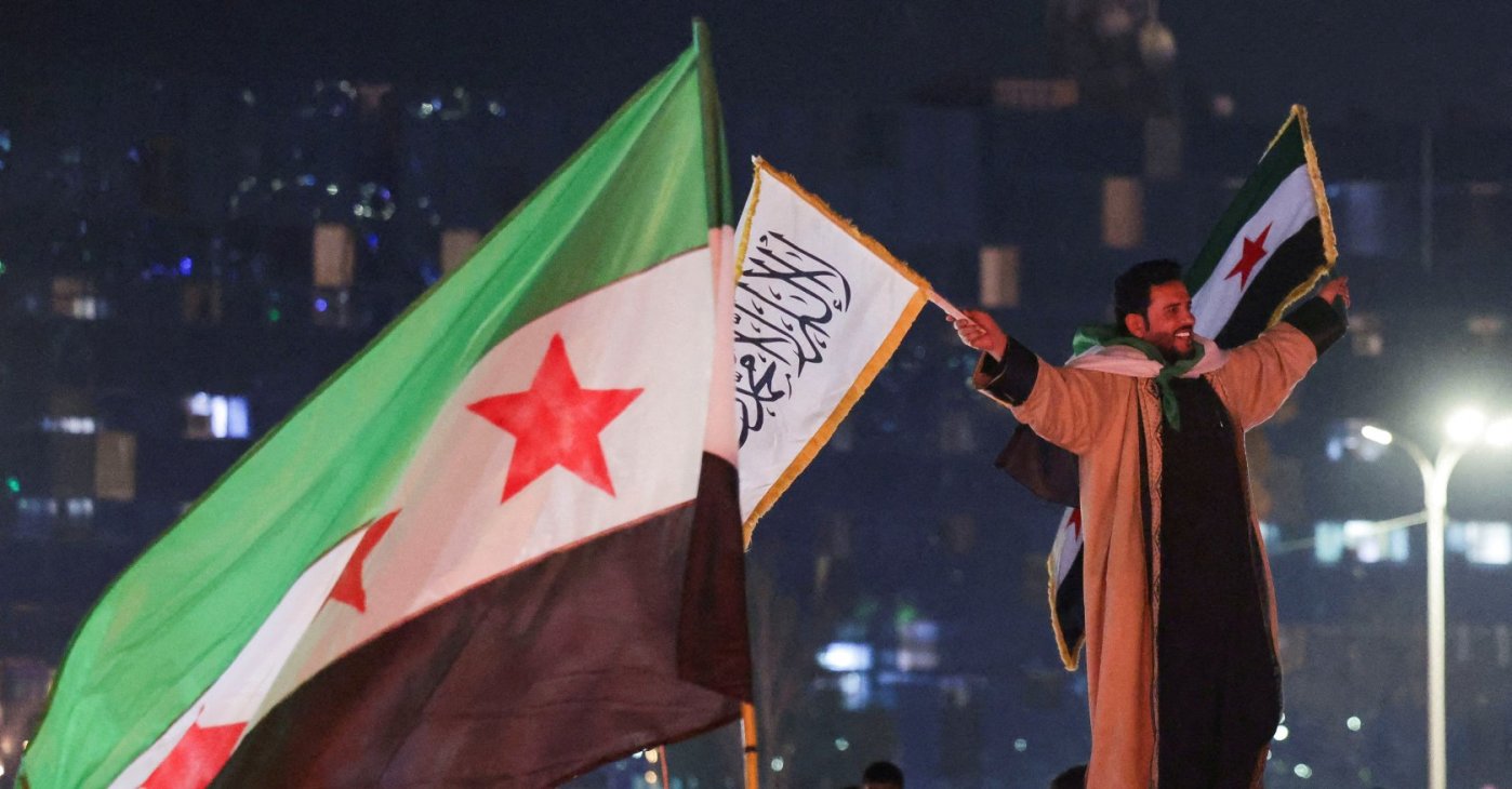A person holds flags as people celebrate after the U.S.-backed YPG terrorist group signed a deal agreeing to integrate into Syria's new state institutions, Damascus, Syria, March 11, 2025. (Reuters Photo)