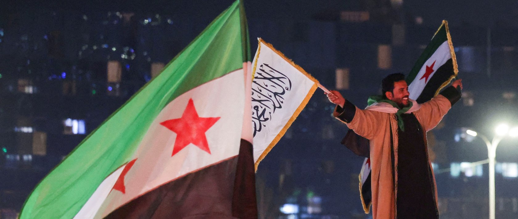 A person holds flags as people celebrate after the U.S.-backed YPG terrorist group signed a deal agreeing to integrate into Syria's new state institutions, Damascus, Syria, March 11, 2025. (Reuters Photo)