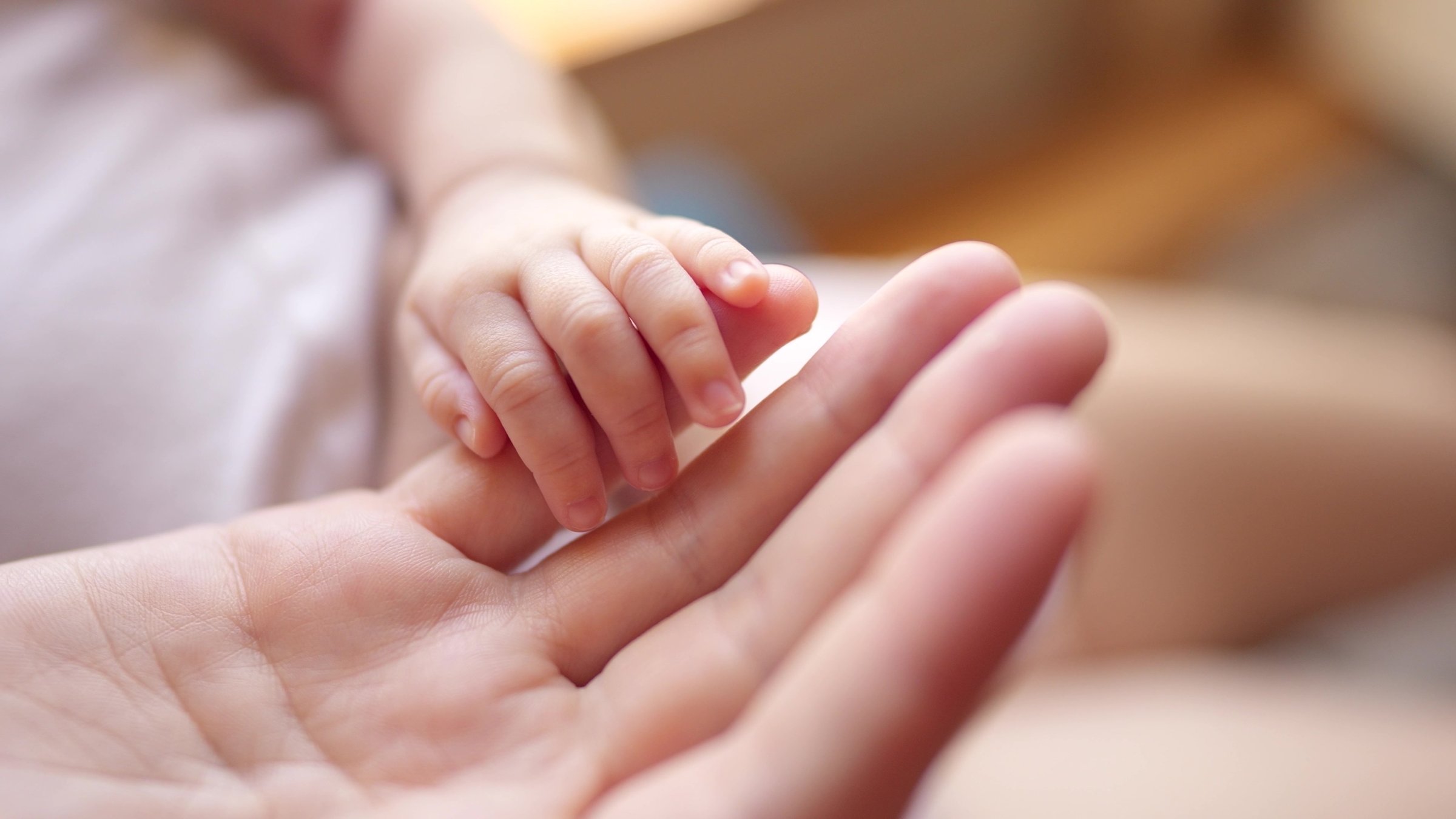 A mother gently holds her newborn’s hand. (Shutterstock Photo) 