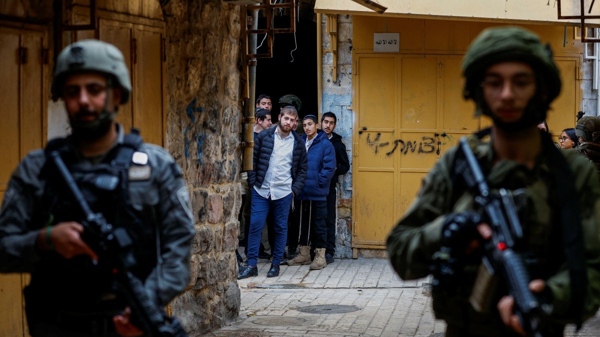 Israelis look at troops standing guard during a weekly settlers' tour in Hebron, in the Israeli-occupied West Bank, Dec. 13, 2025. (Reuters Photo)
