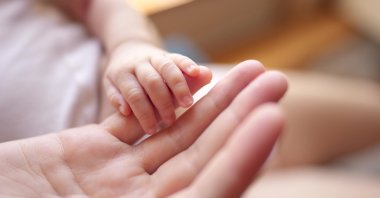 A mother gently holds her newborn’s hand. (Shutterstock Photo) 