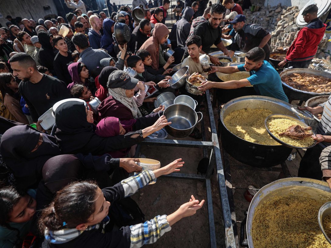 Displaced Palestinians gather to receive food portions at a charity kitchen in the Nuseirat refugee camp, central Gaza Strip, Palestine, Dec. 20, 2025. (AFP Photo)