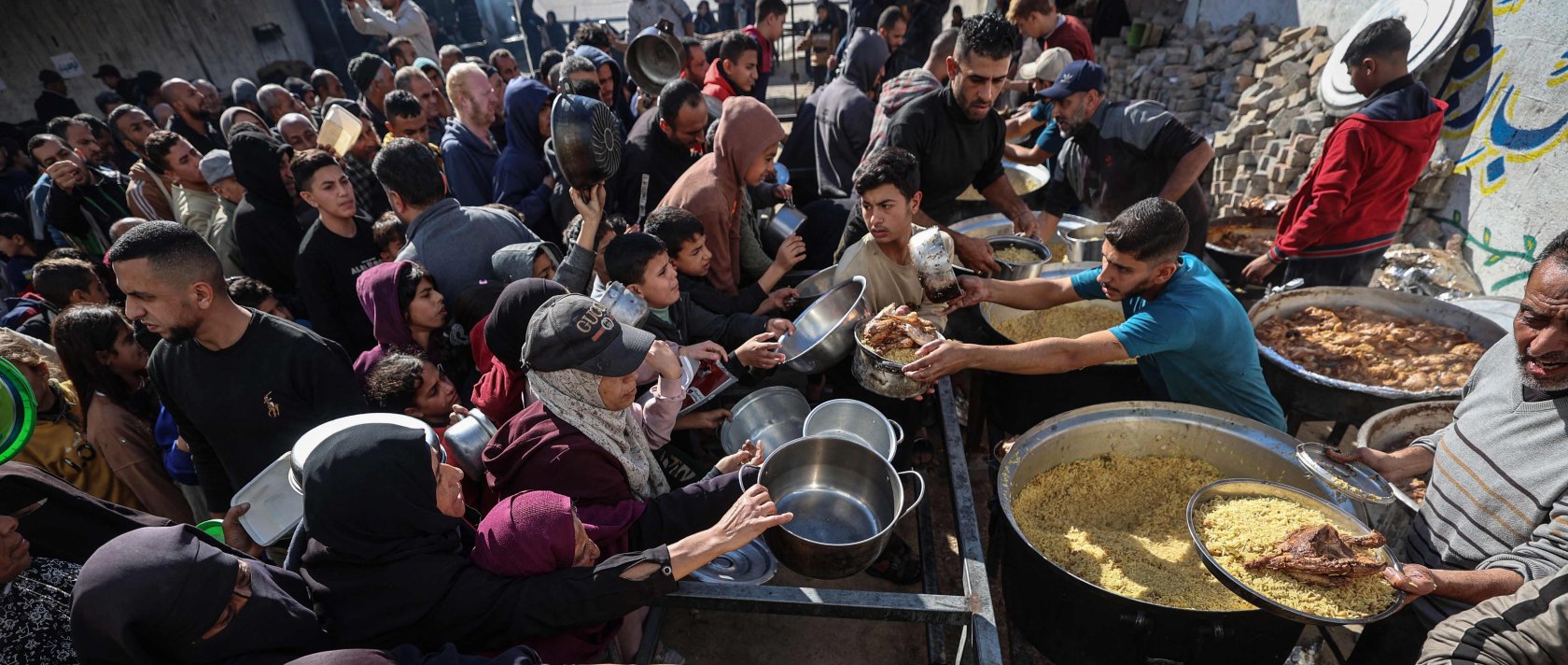 Displaced Palestinians gather to receive food portions at a charity kitchen in the Nuseirat refugee camp, central Gaza Strip, Palestine, Dec. 20, 2025. (AFP Photo)