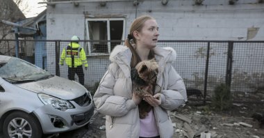 A woman holds her dog near the site of a Russian strike on a home in Zaporizhzhia, southeastern Ukraine, Dec. 19, 2025. (EPA Photo)
