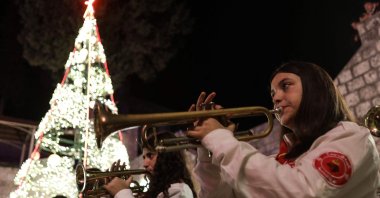 A scout's band plays as residents gather near a lit Christmas tree as they prepare for the upcoming Christmas festivities in the mainly Christian village of al-Qanayyah, Idlib, Syria, Dec. 20, 2025. (AFP Photo)