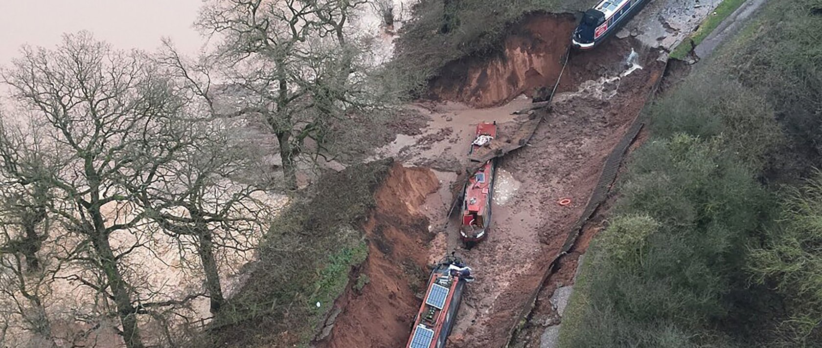 This handout aerial photo taken and released by the Shropshire Fire and Rescue Service shows boats on the bed of the canal after a sinkhole developed along the Shropshire Union Canal, draining the water, in the Chemistry area of Whitchurch, Shropshire, central England, Dec. 22, 2025. (AFP Photo)