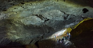Visitors explore prehistoric rock paintings in Shulgan-Tash Cave, Bashkortostan, Russia. (Shutterstock Photo)