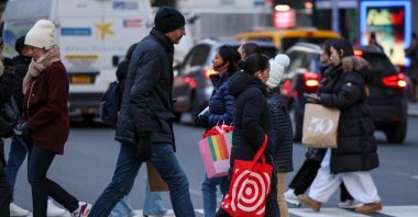 People hold shopping bags as they make their way through Herald Square in New York City, U.S., Dec. 11, 2025. (AFP Photo)
