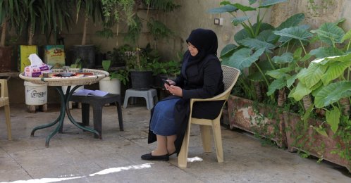 A woman checks her phone while sitting in her home garden in Damascus, Syria, Nov. 23, 2025. (Reuters Photo)
