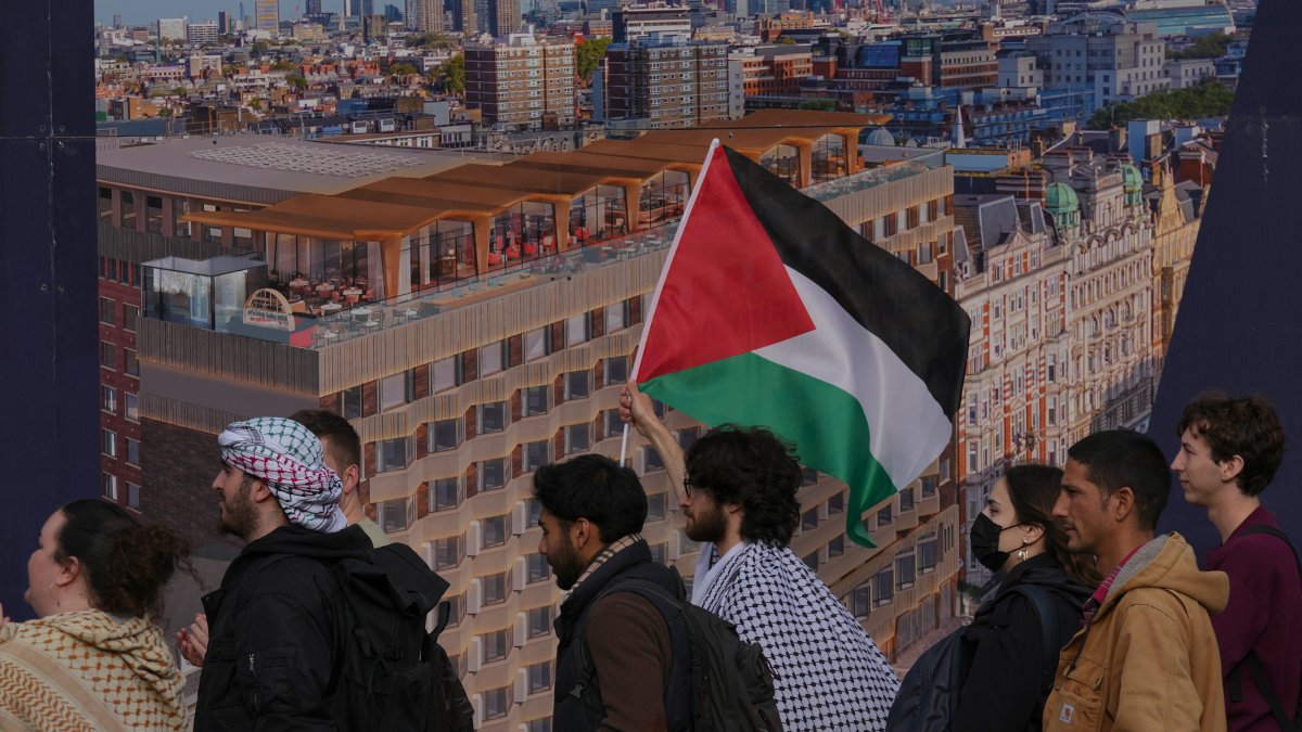 Students walk past a poster of the skyline of London as they take part in a demonstration holding banners, placards and flags during an Inter-university march for Gaza, London, U.K., Oct. 7, 2025. (AP Photo)