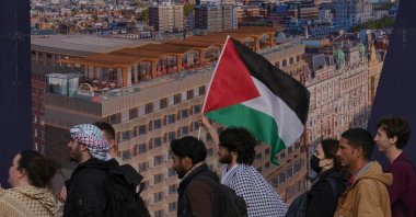 Students walk past a poster of the skyline of London as they take part in a demonstration holding banners, placards and flags during an Inter-university march for Gaza, London, U.K., Oct. 7, 2025. (AP Photo)