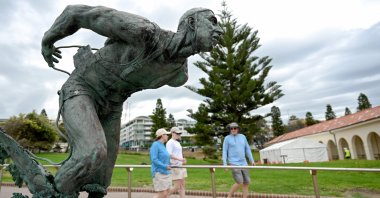People walk past the Surf Life Saver statue at Bondi Beach as life gradually returns to normal following seven days of mourning, in Sydney, Australia, Dec. 22, 2025. (AFP Photo)