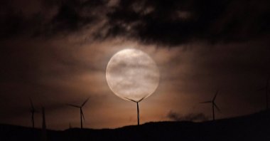 The full moon rises over a wind turbine in Nafplion, Peloponnese region, Greece, Dec. 6, 2025. (EPA Photo)