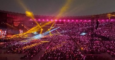 K-pop girl group Blackpink performing at a full stadium as fans wave lightsticks. (Shutterstock Photo)