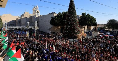 People gather next to the Christmas tree at Manger Square on the day of Christmas events with Cardinal Pierbattista Pizzaballa, Latin Patriarch of Jerusalem, on Christmas Eve, in the Old City of Bethlehem in the Israeli-occupied West Bank, Dec. 24, 2025. (Reuters Photo)