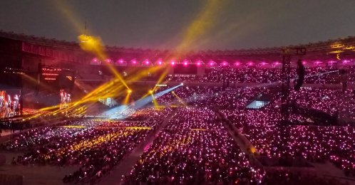 K-pop girl group Blackpink performing at a full stadium as fans wave lightsticks. (Shutterstock Photo)